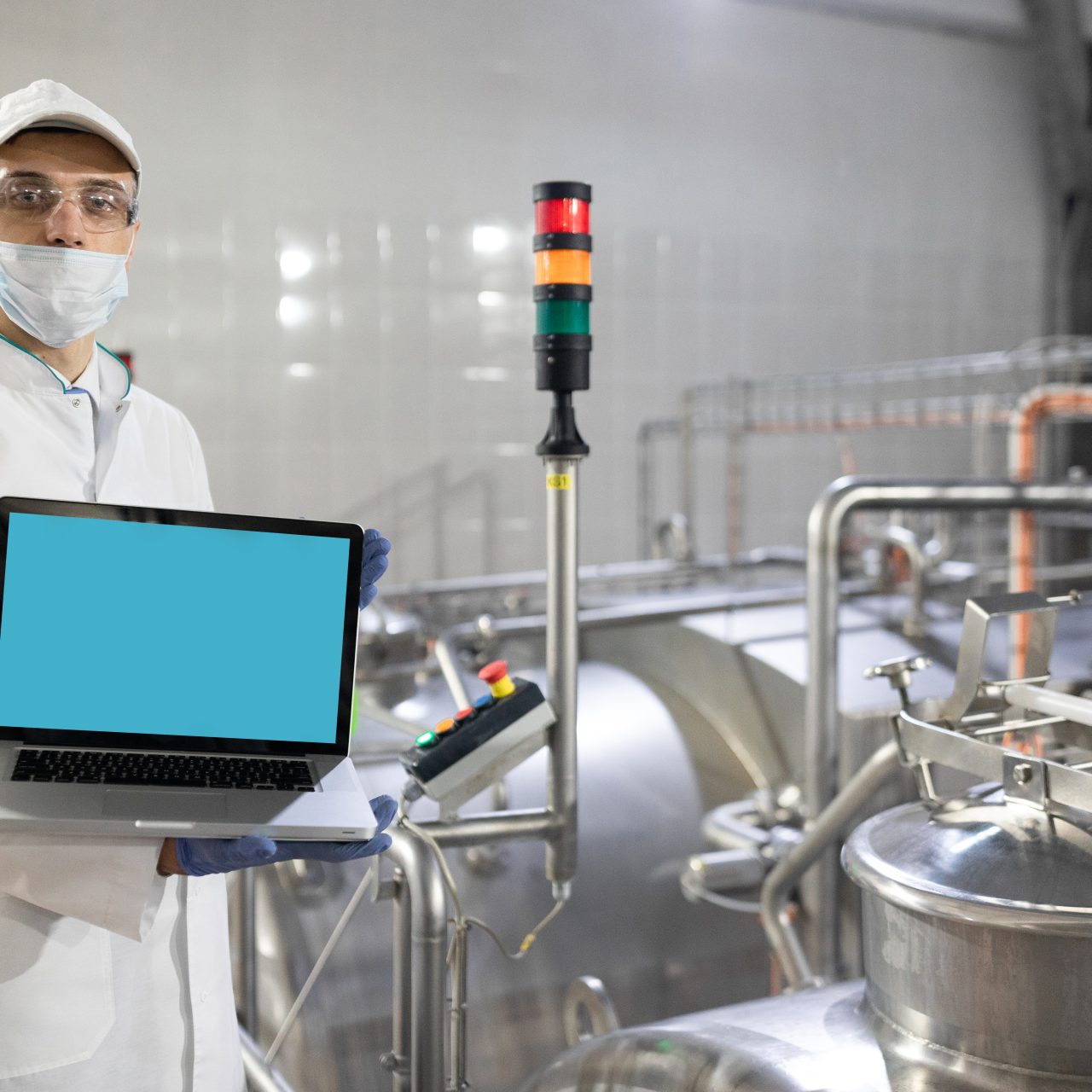 man in a white robe and a mask with a laptop in his hands is at the factory